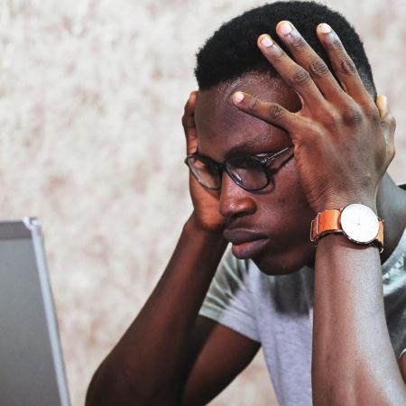 Photo of a man sitting frustrated in front of a computer