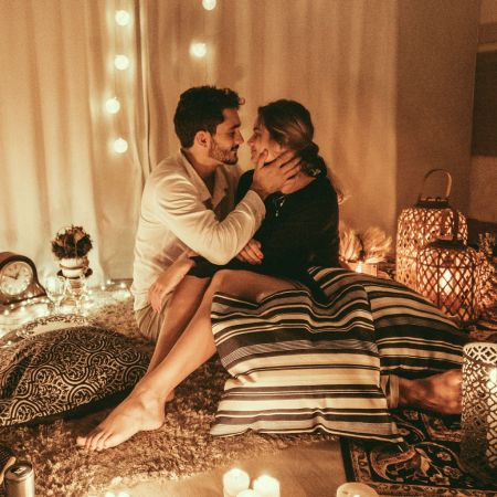 Photo of a love scene. A fully-dressed couple are in each other's arms avout to kiss. TYhere are many spotlights to set the mood.