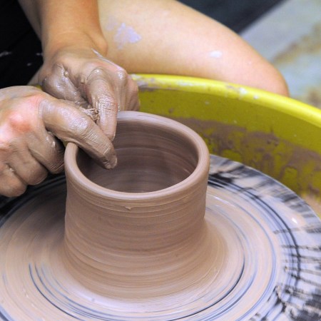 Photo of a potter modelling clay on a wheel.