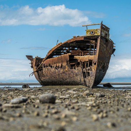 Photograph of an old row-boat, left to decay on the beach.