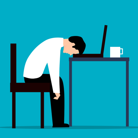 Clipart image of a man at work, slumped over his desk.