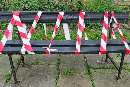A park bench, which has been taped off so it cannot be used.