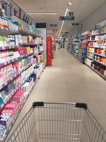 Photo of someone pushing a cart down a supermarket aisle.