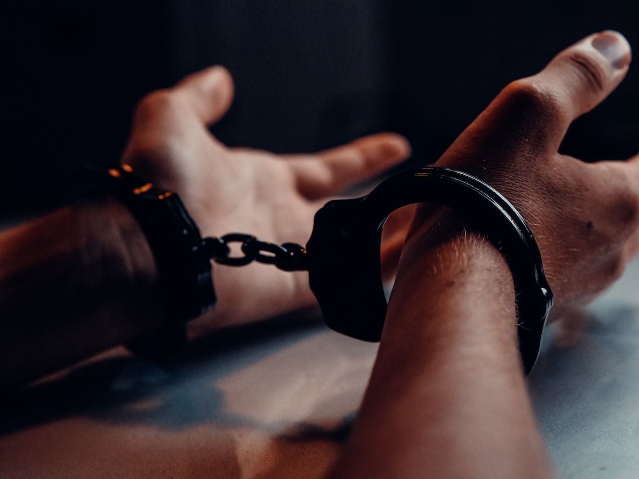 Photo of a man's handcuffed hands.